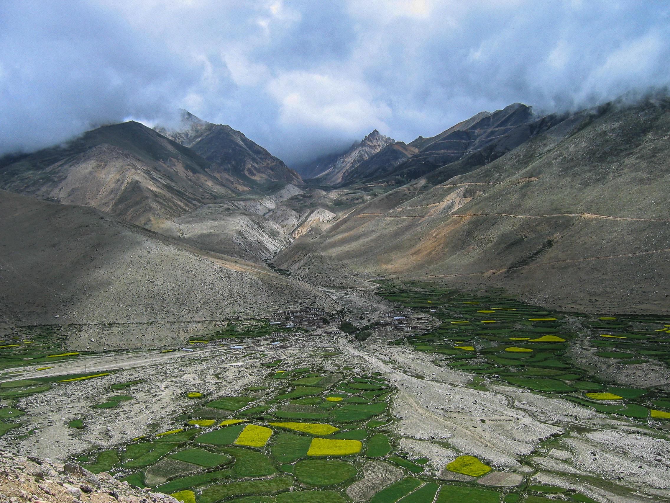 Spectacular Tibetan plateau with fields and high mountains in the distance.