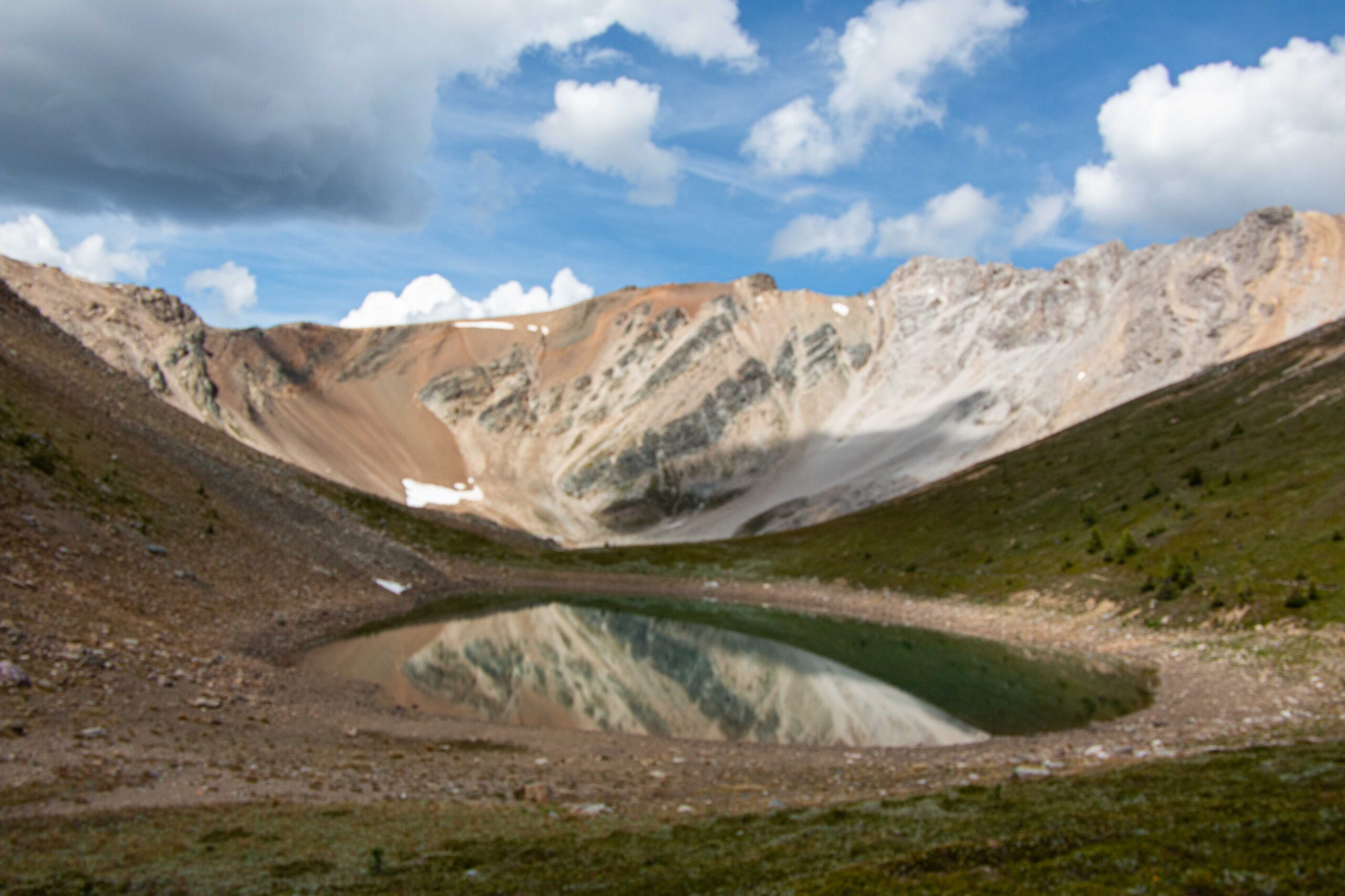 A small lake reflecting the russet tones of the mountains in the background
